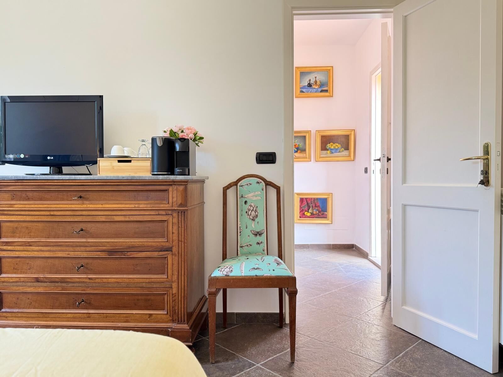 Un dormitorio con un aparador de madera, un televisor y una silla con un cojín estampado con flores.