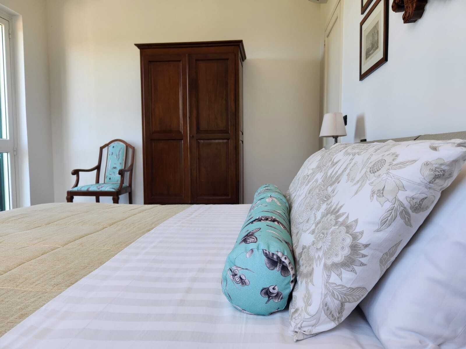 Una camera da letto con un letto grande, un armadio in legno, una sedia e una lampada a parete.