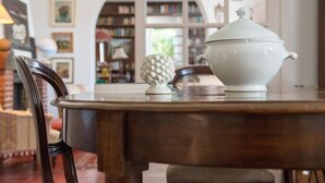 A wooden table with a white ceramic pot and a pineapple-shaped object on it. - Don Gaspano  (Pace del Mela)