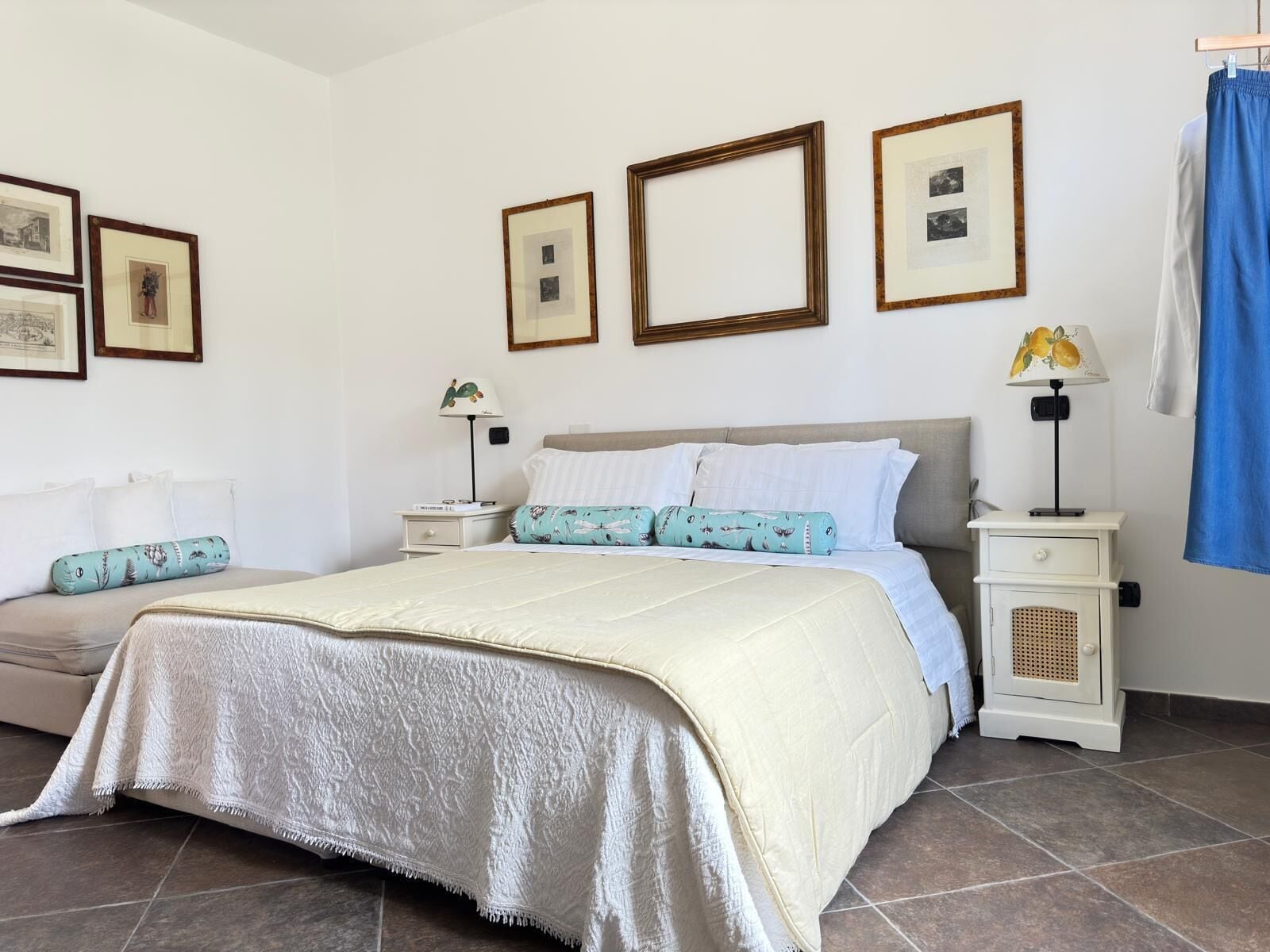 A neatly arranged bedroom with a bed, bedside tables, a lamp, and framed pictures on the wall.