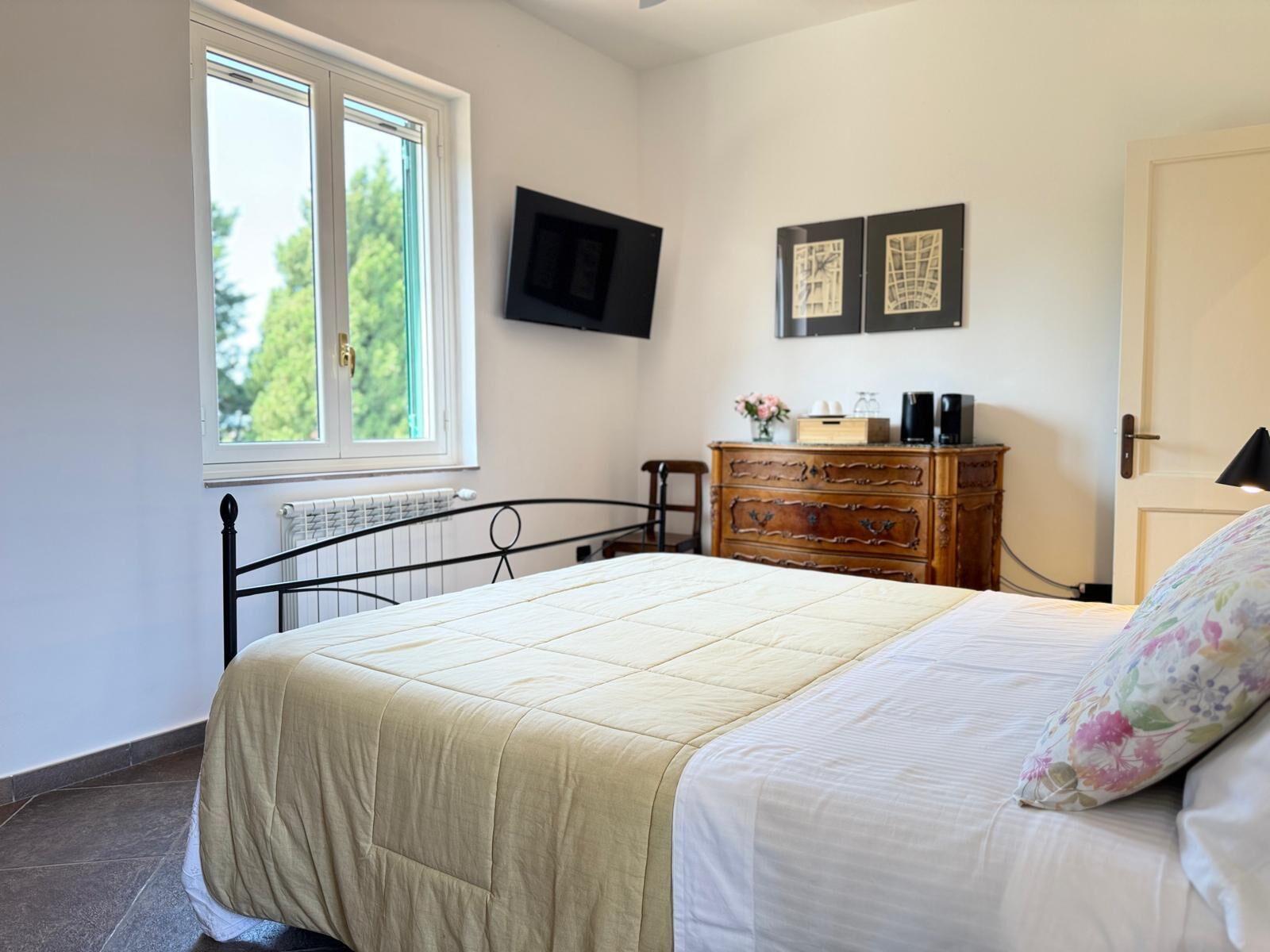 Ein Schlafzimmer mit Bett, Kommode, Fernseher und Fenster.