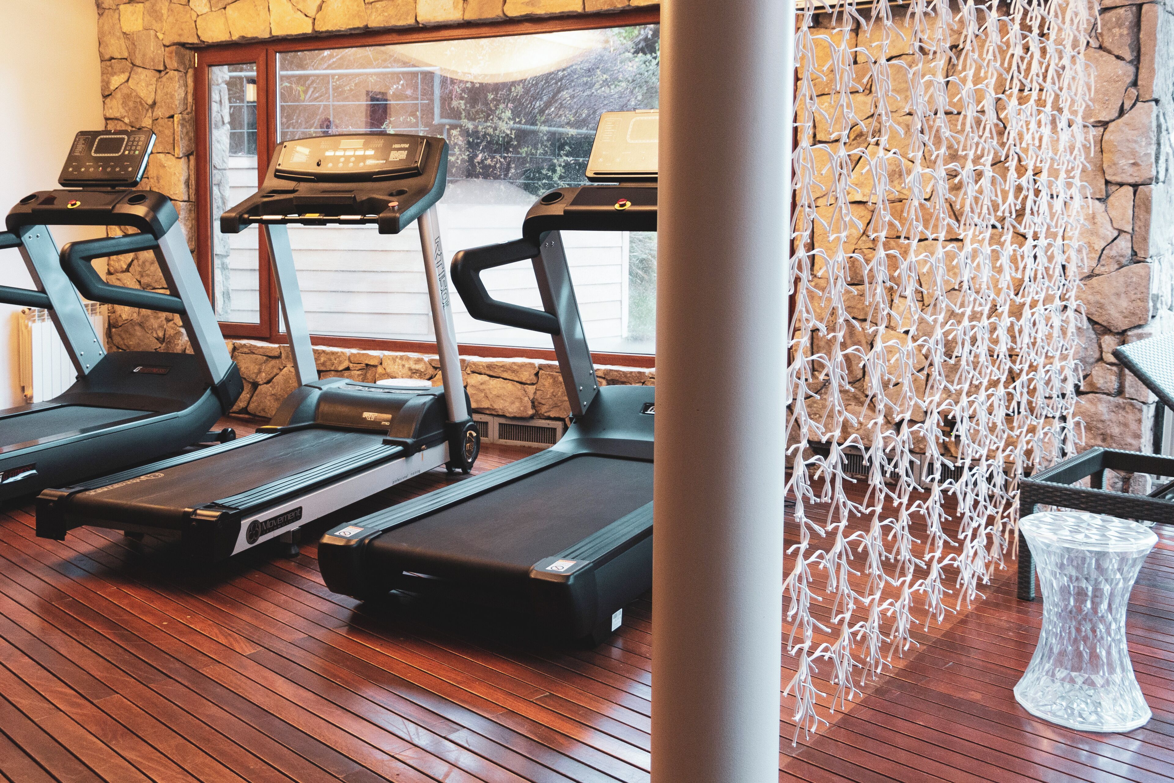 A gym with treadmills and a stone wall.