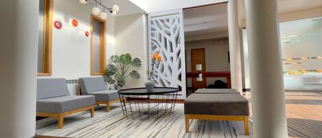 Un vestíbulo moderno con zona de estar, una planta decorativa y un separador blanco.