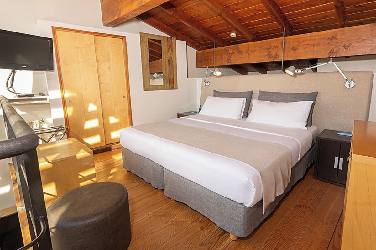 Une chambre à coucher avec un lit, des tables de chevet, un bureau et un téléviseur.