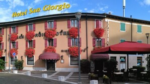 Hotel San Giorgio met een rood luifel, bloembakken onder de ramen en terraszitplaatsen.