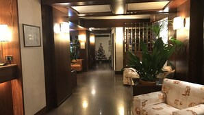 Een hotel lobby met een receptiebalie, een kerstboom, een bank en een grote plant.
