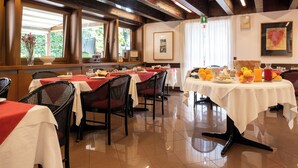 Een restaurant met meerdere tafels en stoelen, een betegelde vloer en een houten plafond.