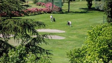 Un campo da golf con un verde curato, bunker sabbiosi e una vegetazione rigogliosa.