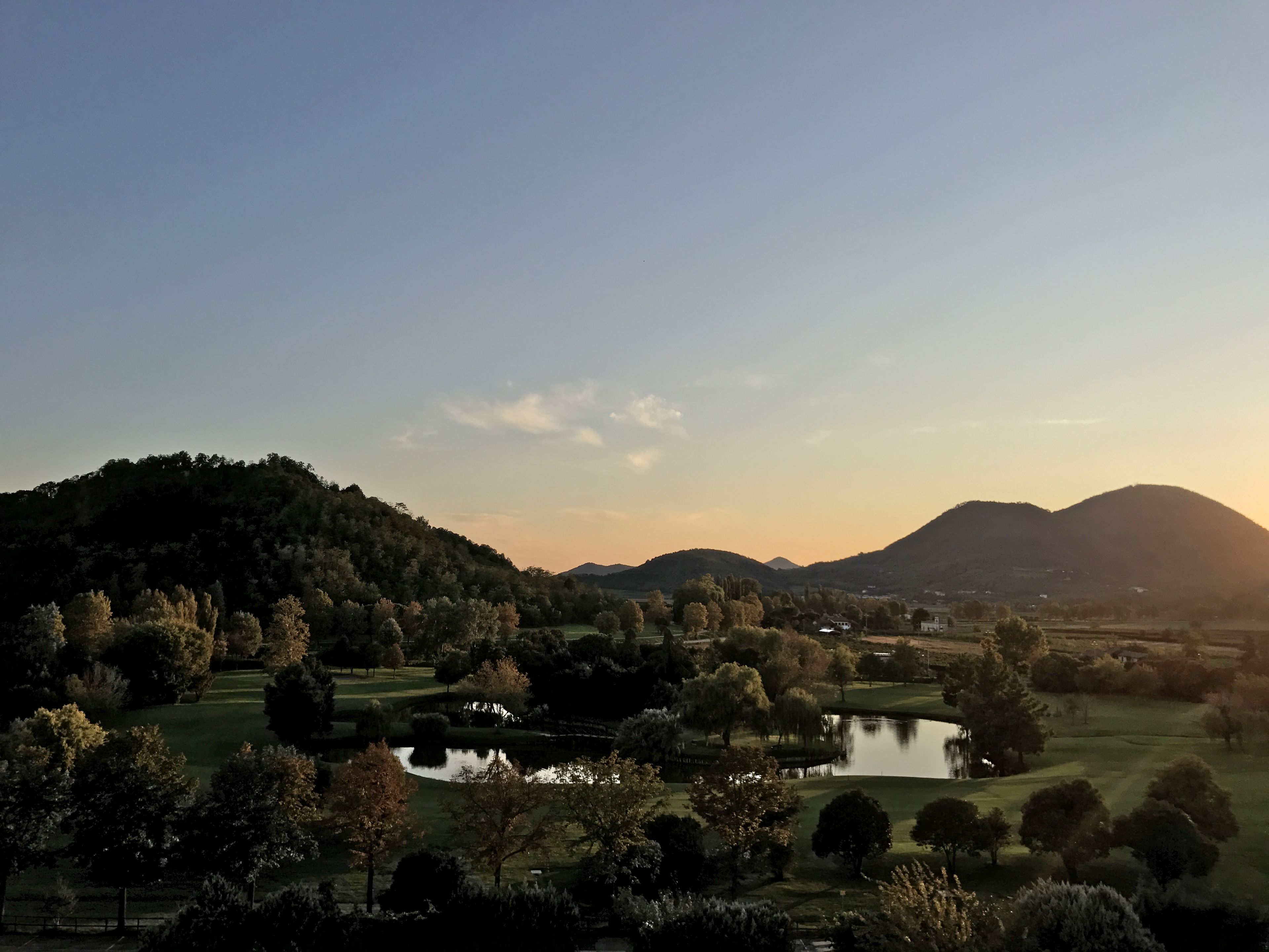 A serene landscape with a lake, trees, and distant hills.