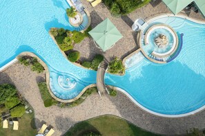 A large, winding pool with a central water feature, surrounded by lounge chairs and umbrellas. - Galzignano Resort Terme & Golf - Hotel Sporting (Galzignano Terme)