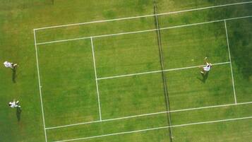 Vista aérea de uma quadra de tênis com jogadores em movimento.