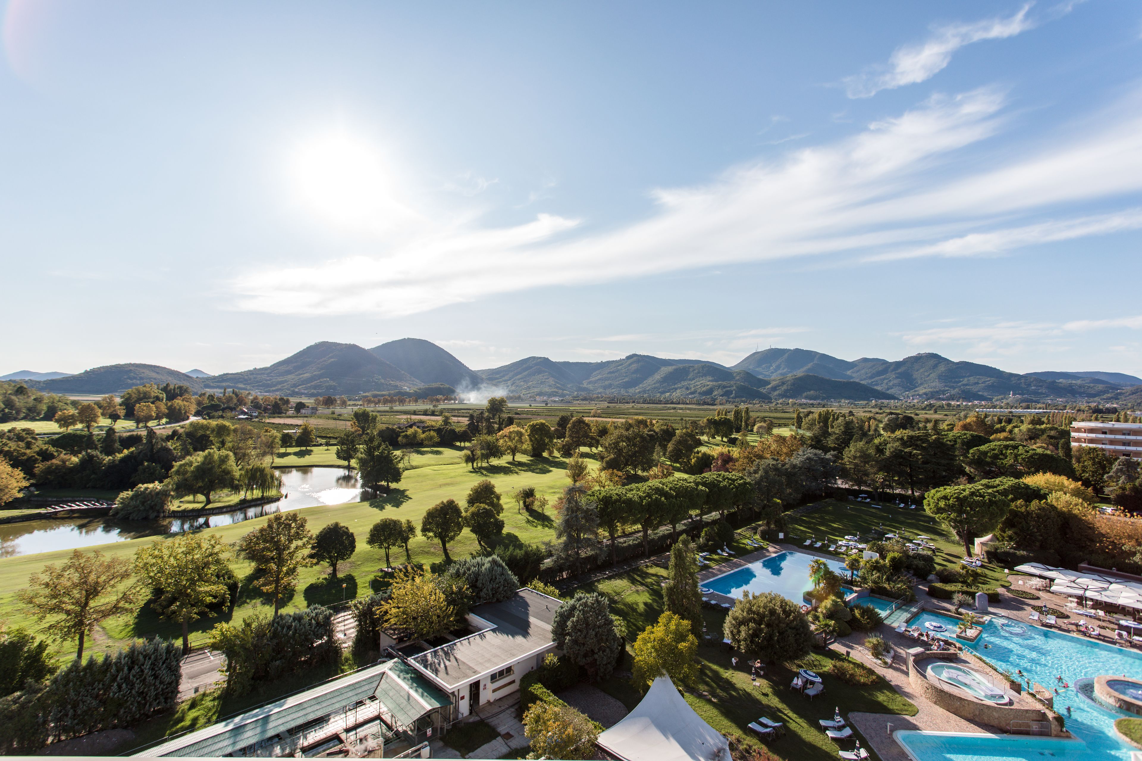 Un resort con una amplia piscina, canchas de tenis y un paisaje montañoso.