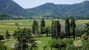A golf course with a view of a town in the distance, surrounded by hills and trees.