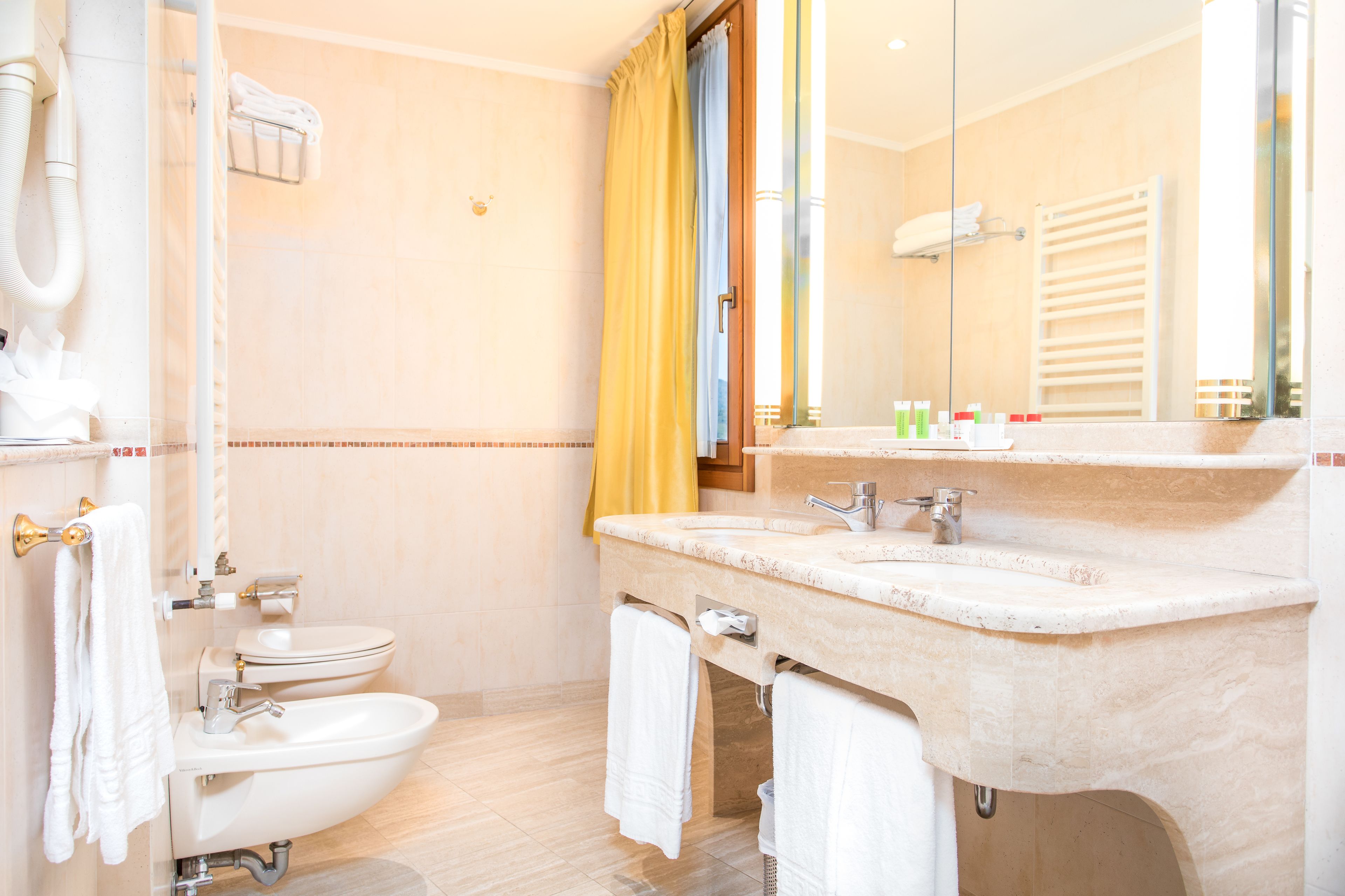 Un baño con inodoro, bidé, lavabo y espejo.