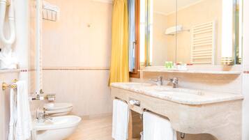 Un baño con inodoro, bidé, lavabo y espejo.