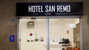 The entrance to Hotel San Remo with a clear view of the reception area, including a desk, chairs, and a fire extinguisher. - Hotel San Remo (Alicante)