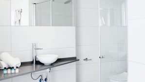 A modern bathroom with a white sink, mirror, and glass shower enclosure. - Hotel San Remo (Alicante)