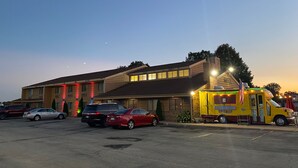 Un hôtel doté d’un parking, d’un camion-restaurant jaune et de plusieurs voitures garées.