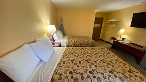 Une chambre d’hôtel avec deux lits, chacun agrémenté de draps blancs et d’une couvre-lit à motifs. On y trouve des tables de chevet avec des lampes, un bureau avec une chaise et un téléviseur fixé au mur.