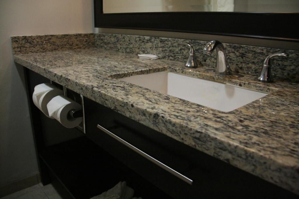 Un bagno con un piano in granito, un lavandino bianco e un portasciugamani.