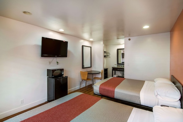 Una habitación de hotel con dos camas, un televisor, un escritorio y una silla.