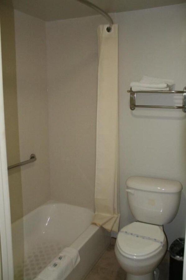 Un baño con bañera, inodoro y cortina de ducha.