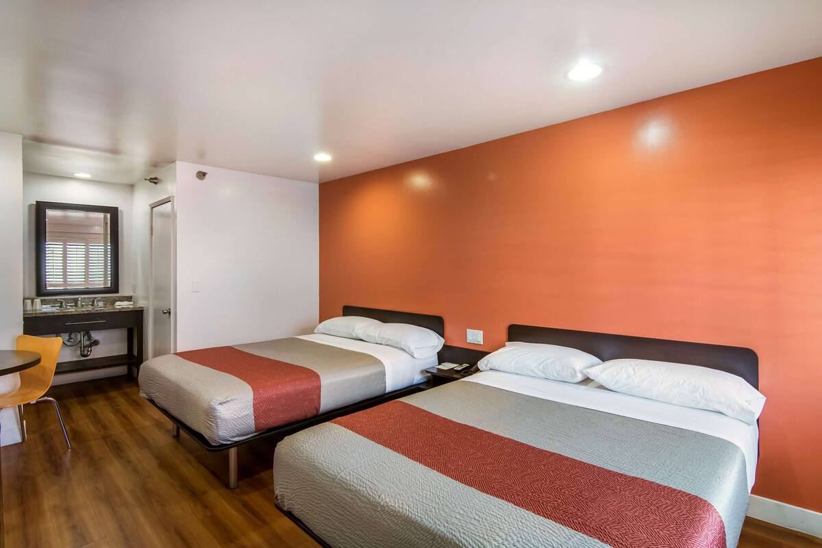 A room with two beds, a desk, and a chair.