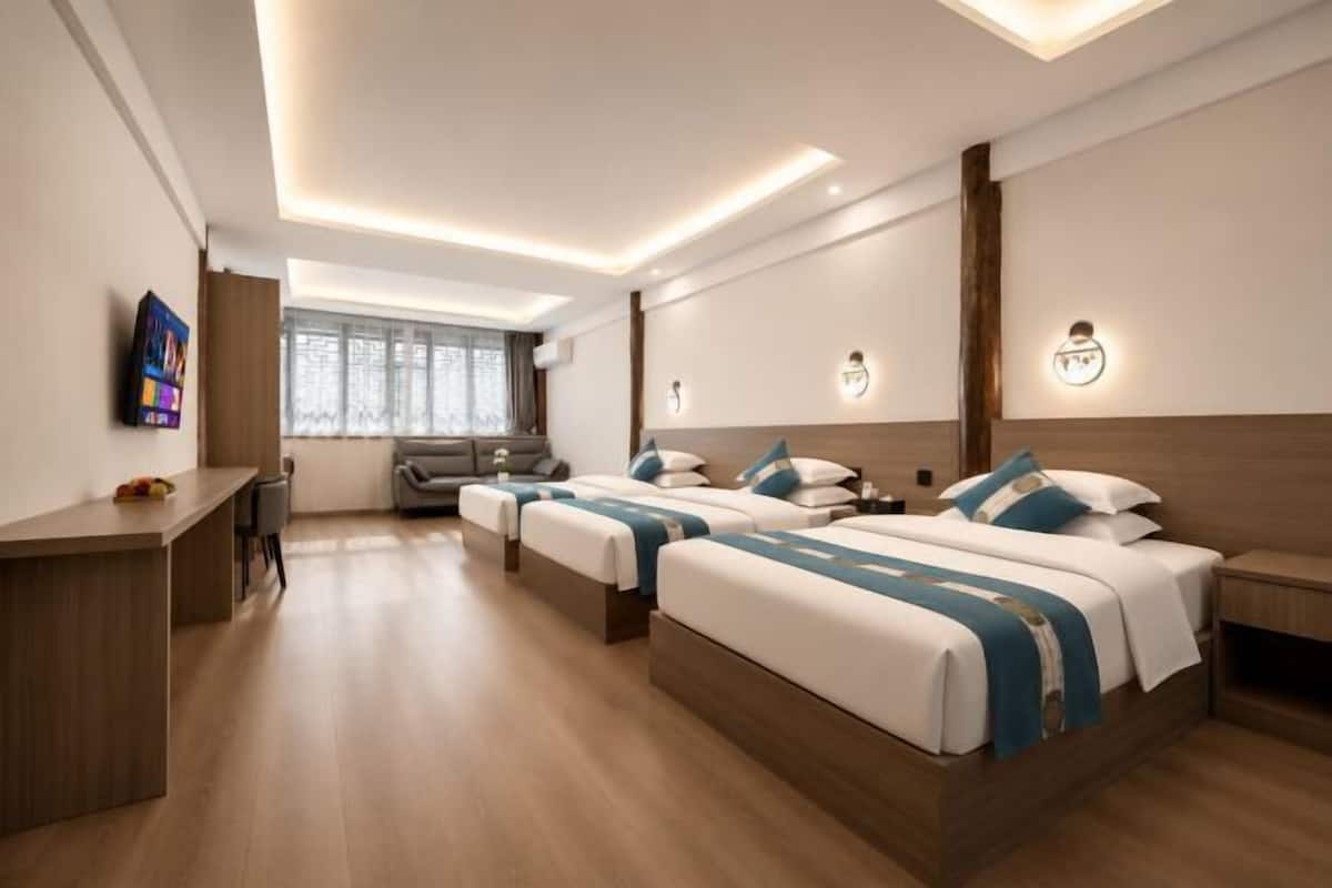 Habitación de hotel con dos camas, un escritorio, un televisor y una ventana.