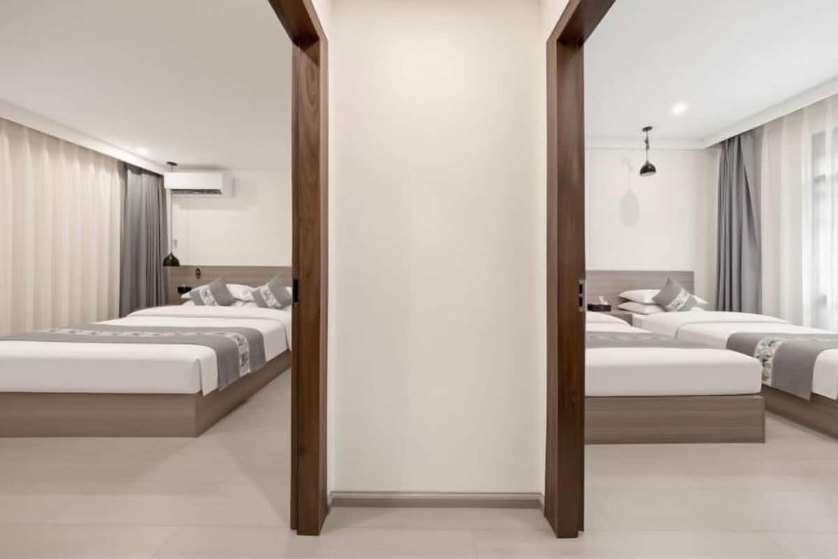 Una habitación de hotel moderna con dos camas, un espejo grande y suelo de madera.