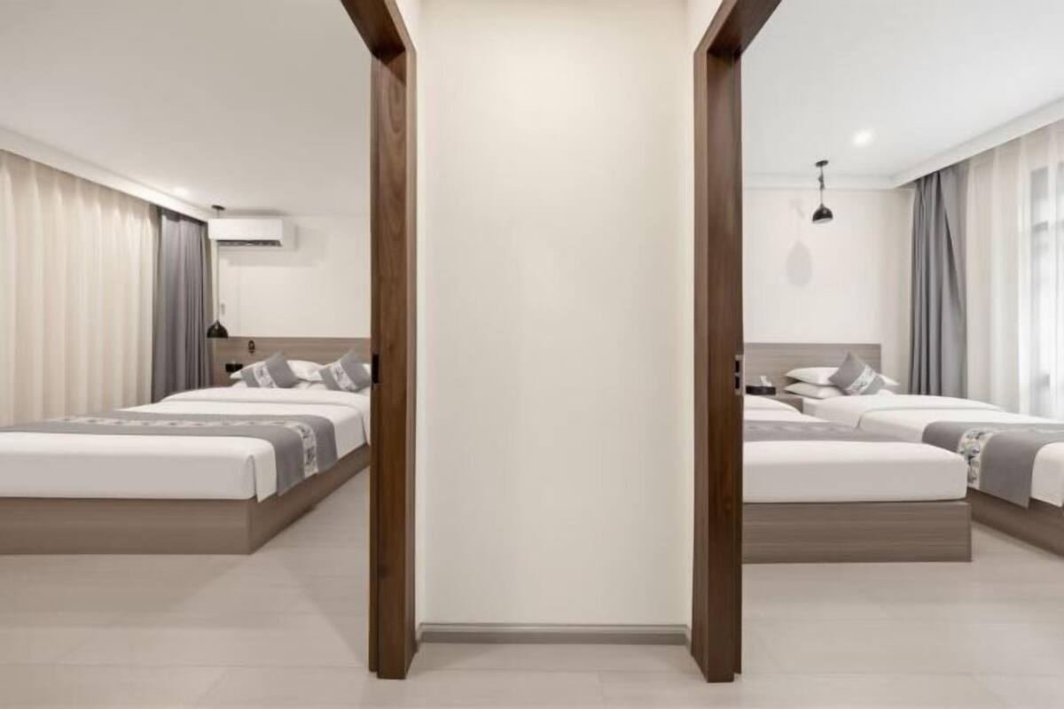 A modern hotel room with two beds, a large mirror, and a wooden floor.