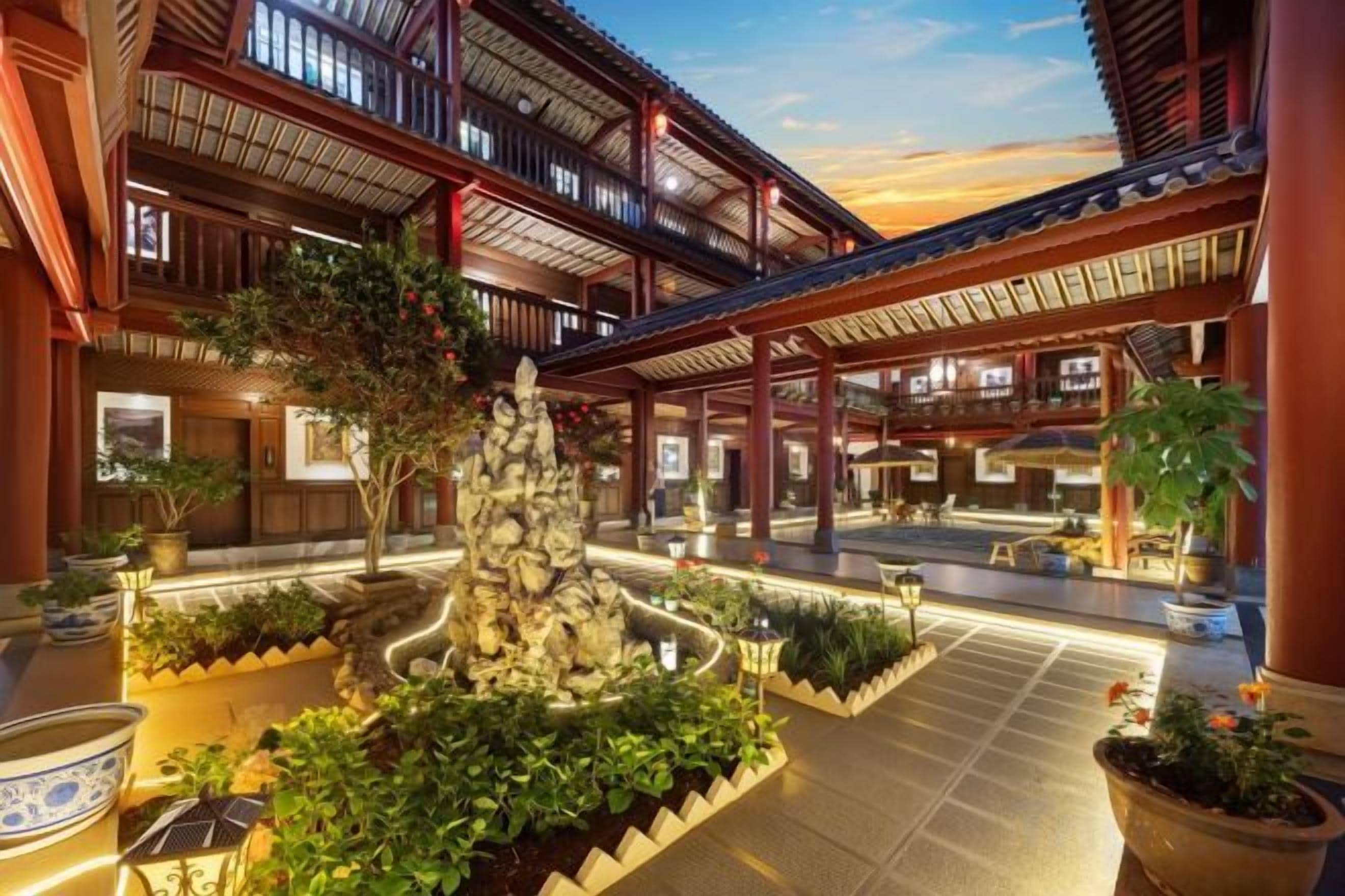 A traditional building with multiple balconies, a central courtyard with a rock feature, and potted plants.