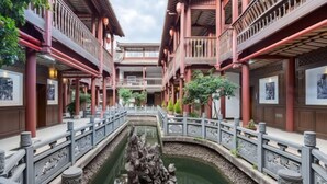 Un patio tradicional con una fuente central, edificios de madera con balcones y obras de arte enmarcadas en las paredes.