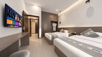 A modern hotel room with two beds, a TV, a desk, and a walk-in closet.