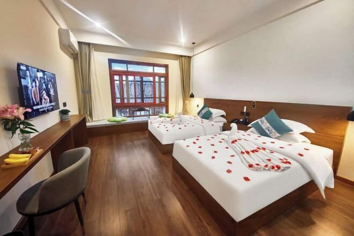 Habitación de hotel con dos camas, un escritorio, una televisión y ventana con vistas.