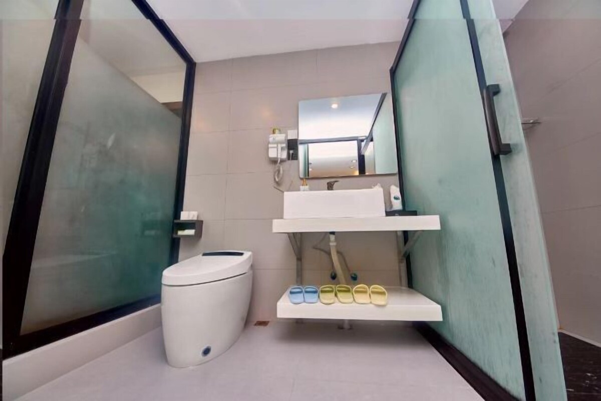 Un baño moderno con inodoro, lavabo, espejo y cabina de ducha de vidrio.