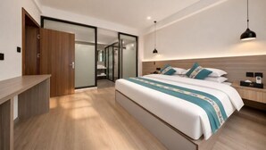 Una habitación de hotel moderna con una cama grande, un escritorio, un armario y una puerta corredera que da a un baño.