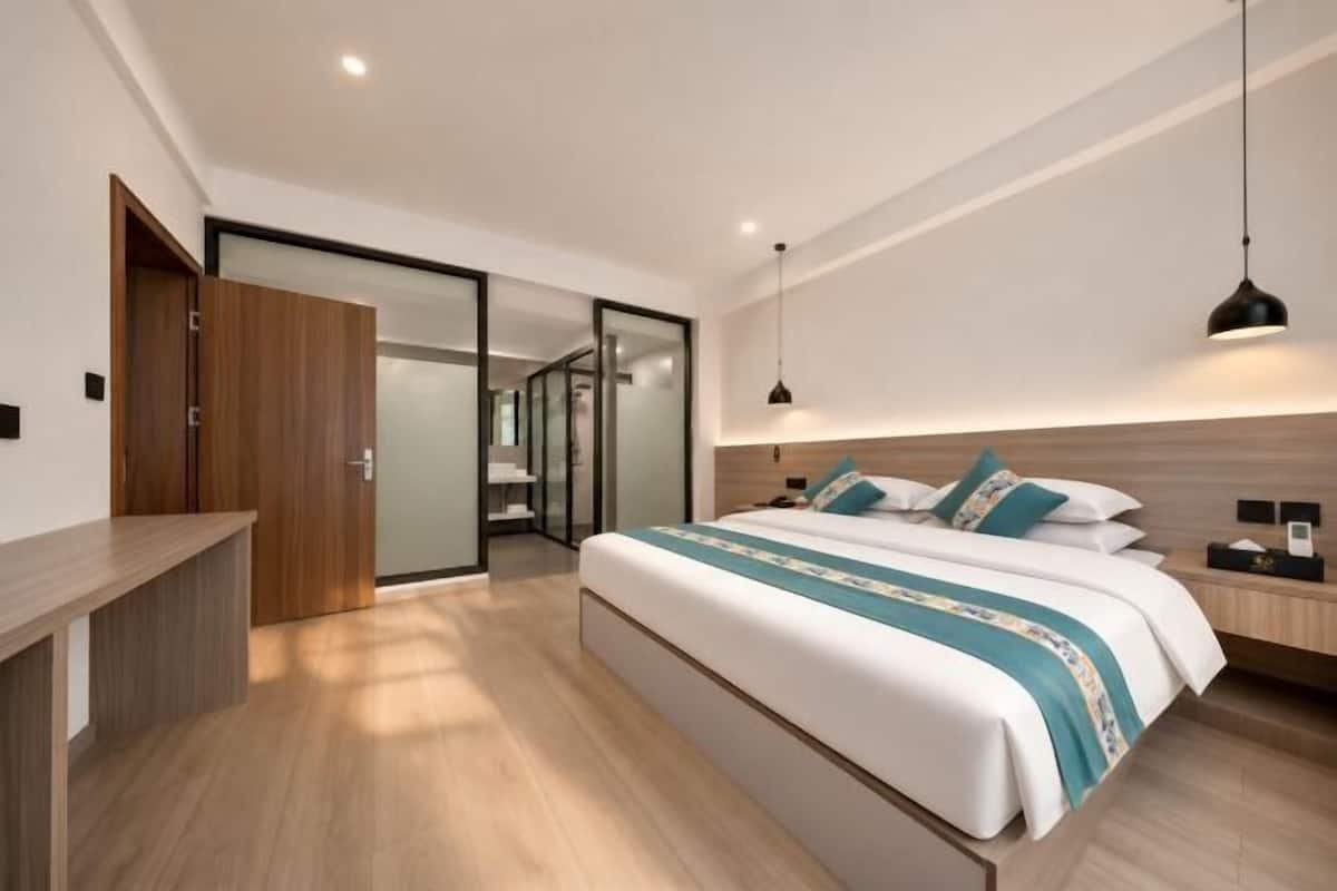 Una habitación de hotel moderna con una cama grande, un escritorio, un armario y una puerta corredera que da a un baño.