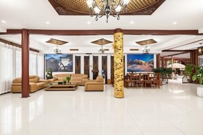 A spacious lobby with a high ceiling, a central column, a chandelier, a large painting, and a dining area. - Old Town of Lijiang Tianxiangge Hotel (Old Town of Lijiang South Store) (Lijiang)