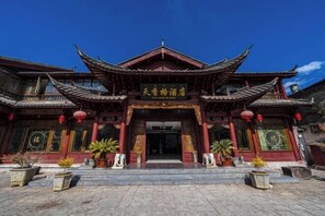Un edificio chino tradicional con una entrada destacada, techo ornamentado y farolillos rojos.