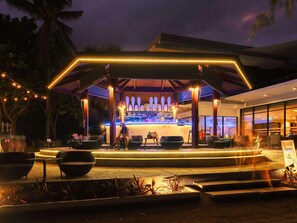An outdoor bar area with a covered seating arrangement, a bar counter, and a pool. - Splash Beach Resort, Maikhao Phuket (Mai Khao)