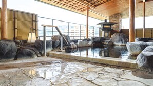 A traditional Japanese onsen with stone flooring, a wooden ceiling, and a stone lantern. - Hotel Wakamizu (Takarazuka)