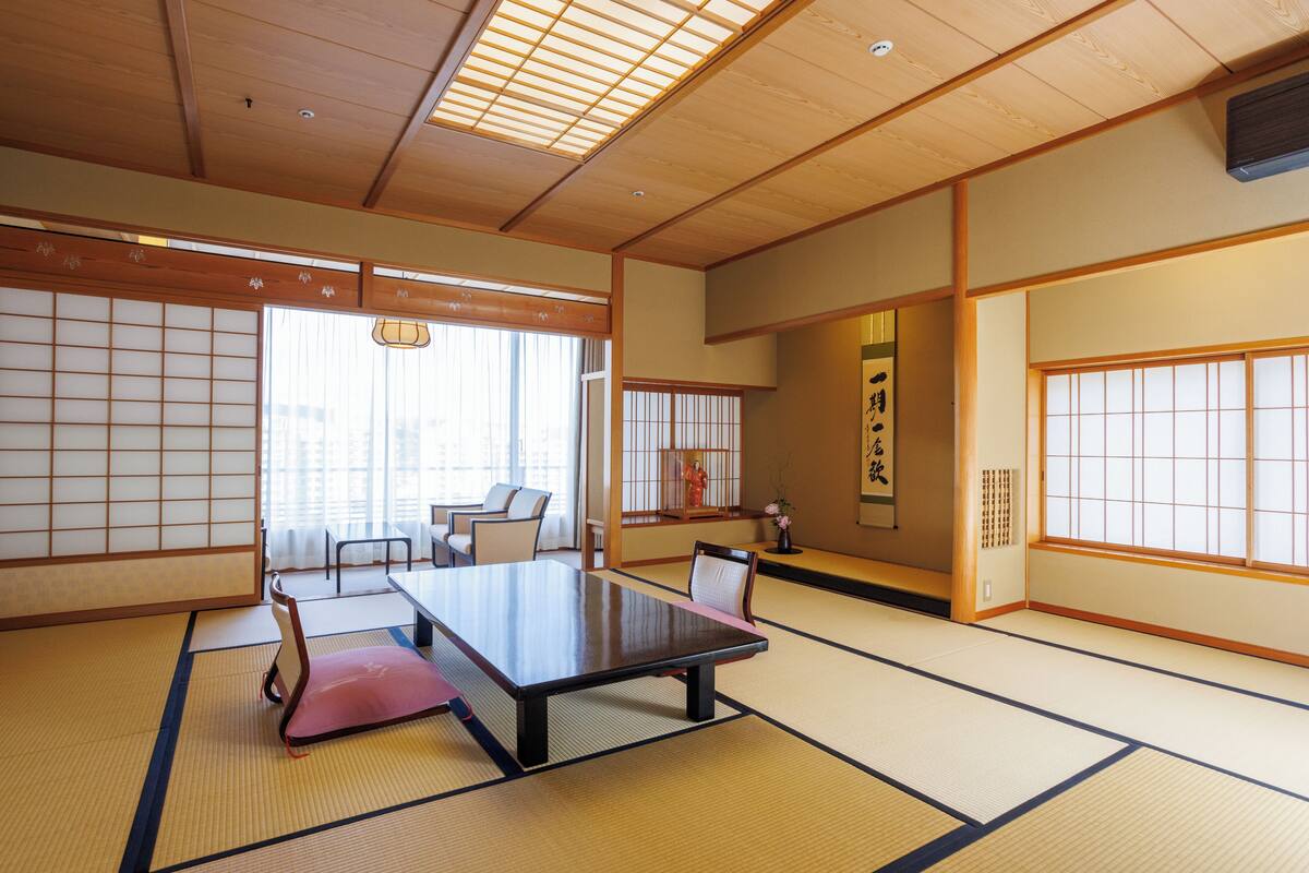 A traditional Japanese room with tatami flooring, a low table, and a seating area with cushions.
