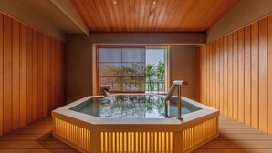A hot tub in a wooden room with a view of greenery outside. - Hotel Wakamizu (Takarazuka)