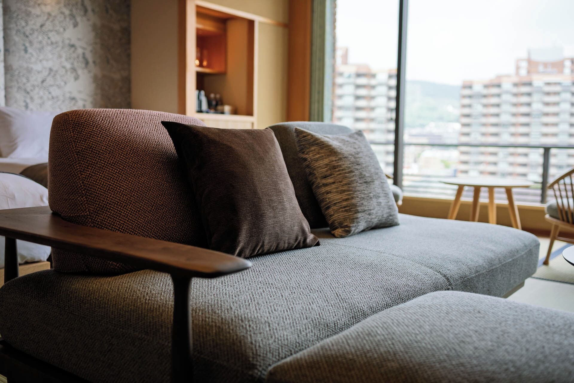 A modern living room with a grey sofa, two dark brown pillows, and a wooden coffee table.