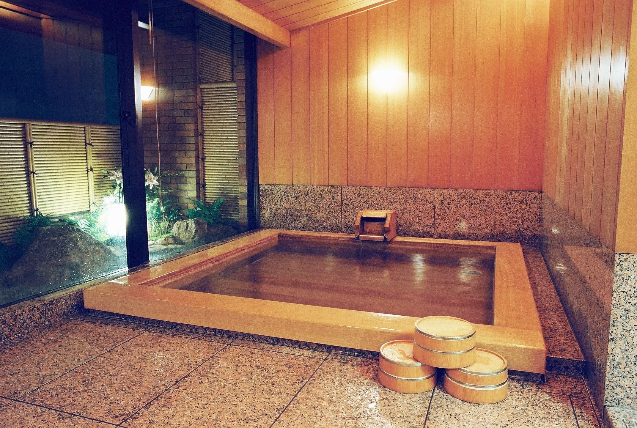 A wooden-floored hot tub with a small wooden stool and three wooden buckets.