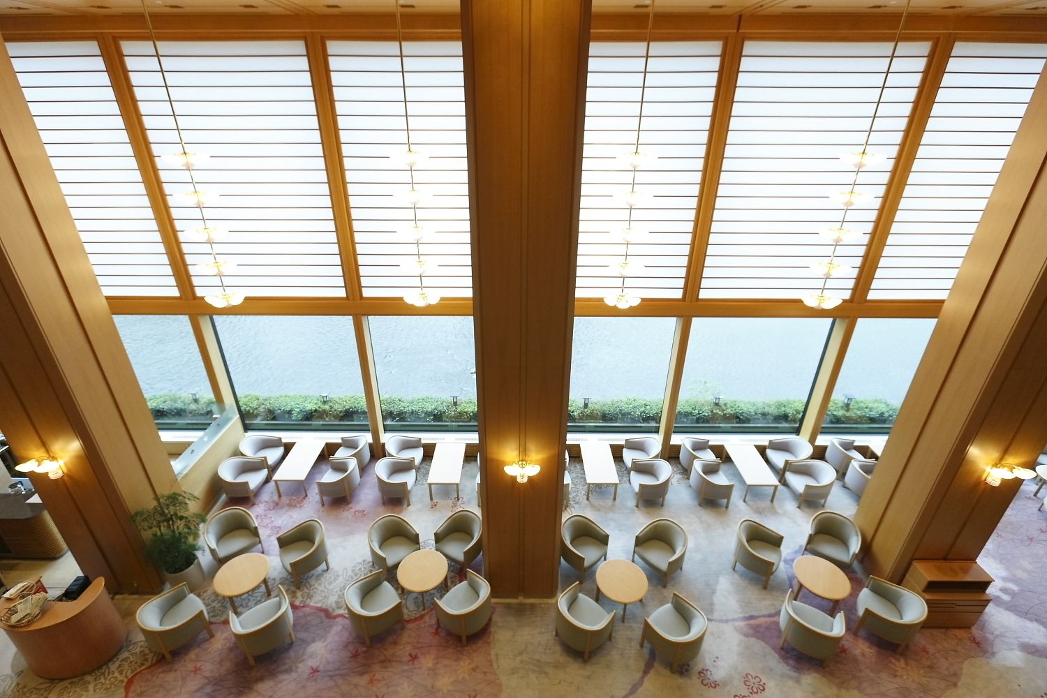 A spacious indoor area with multiple seating arrangements, large windows, and a view of the outdoors.