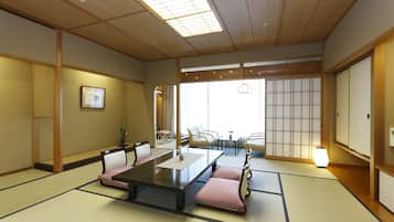 Una habitación japonesa tradicional con suelo de tatami, una mesa baja con cojines y puertas correderas.