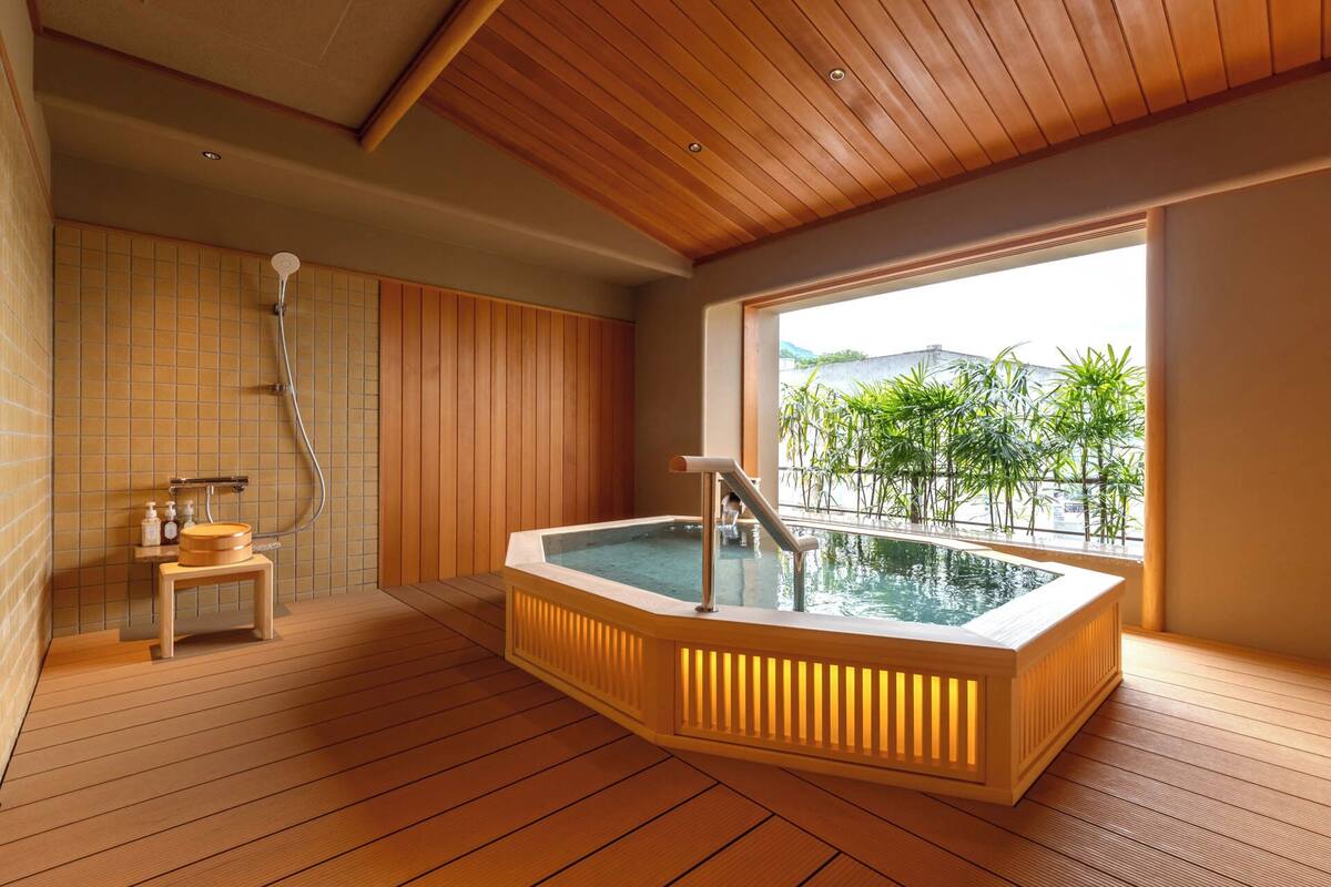 A spa room with a wooden floor, a hot tub, and a view of greenery outside.