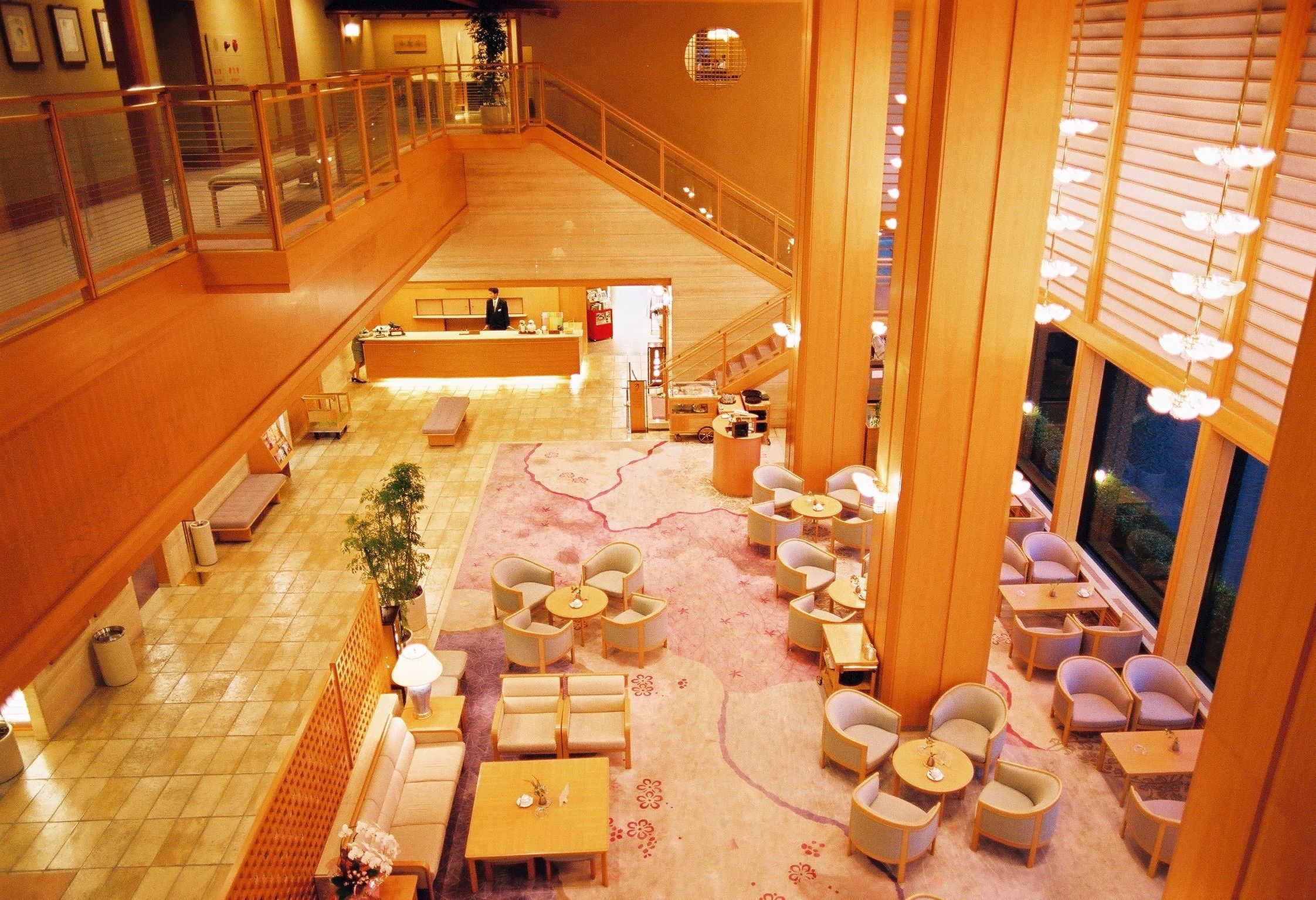 A spacious lobby with a central seating area, a staircase, and a reception desk.