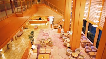 A spacious lobby with a central seating area, a staircase, and a reception desk.